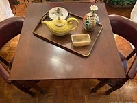 Wooden tall breakfast table with various decorative items on top, including the Hall Genie tea pot, Polly vase, marble bowl, and candy dish.