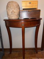 Foyer table holding the Olmec head sculpture and two cigar boxes, showing front view