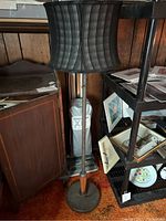 Full view of vintage floor lamp with black fabric shade and metal stand showing wood accent and round base.