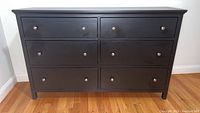 Front view of black wooden chest showing 6 drawers with metal knobs