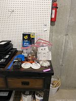 View of lot on table showing bug zapper box, switch plates, light bulb sockets, and other electrical items.