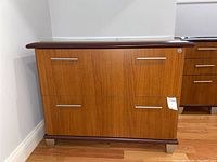 Front view of lateral file cabinet showing two drawers with metal pulls and wood veneer finish, including tags.