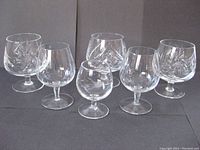 Front view of 6 assorted vintage crystal brandy snifters showing cut and etched patterns.