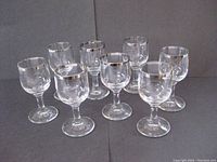 Set of 8 clear crystal schnapps glasses arranged in two rows, showing their silver rims and stems.
