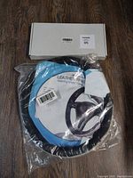 Black leather steering wheel cover in plastic packaging with original box on wooden floor