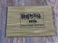 Closed booklet with textured gold cover and Japanese characters on front, dated 1976