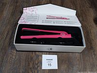 Pro Cabello Classic Hair Straightener inside open box on wooden floor, showing pink straightener with flat plates.