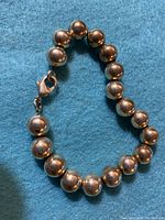 Sterling silver bead bracelet laid flat on blue fabric, showing uniform bead size and lobster clasp closure.