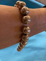 Close-up photo showing the large round polished silver beads strung on chain worn on a wrist.