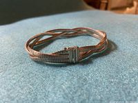 Silver 3-strand braided satin finish bracelet with clasp closed showing texture and shape