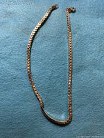 Full view of the 17-inch sterling silver boxed chain necklace laid flat on a blue fabric background.