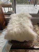 Top surface of the wool rug showing long, curly white wool fibers providing a soft, fluffy texture.