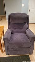 Front view of dark gray velvet rocker recliner showing tufted backrest and padded armrests.