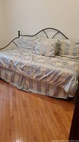 Day bed with satin-like linens in gold and gray shades, showing the front and left sides with pillows arranged.