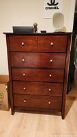 Front view of Coaster 5 drawer dresser showing all drawers, metal knobs, and dark cherry wood finish.