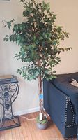 Full view of the faux tree showing its height, potted base, and string lights along the trunk.