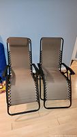 Front view of two brown gravity chairs side by side with metal frames and fabric seats.