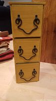 Front view of the wooden 3-drawer storage case with decorative metal handles, showing the condition and drawer structure.