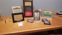 Photo of nine various photo frames arranged on wood table, showing style and size differences