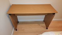 Top view of rolling desk showing rectangular light wood laminate surface with some wear and marks.