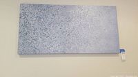 Full view of the rectangular textured wall art panel hanging on a wall showing the overall size and shape with grey and blue speckled design.