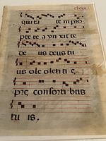 Close-up of illuminated monastery chant manuscript page, showing square musical notes and worn parchment