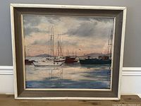 Frontal view of the framed seascape painting showing boats on calm water with cloudy sky and mountains.