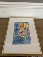 Framed watercolour painting of colorful flowers on a blue background, showing entire artwork and frame.