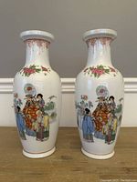 Full view of the pair of Chinese porcelain vases on a wooden surface showing their overall shape and painted design.