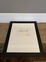 Framed Picasso print of black line drawing dog resting on wooden surface, showing overall condition and style.