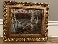 Full front view of the framed oil on board painting showing the detailed gold frame and natural landscape with birch trees near a lake.