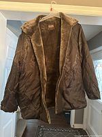 Front view of Danier ladies brown coat with visible plush faux fur inner lining and collar, hanging on clear hanger.