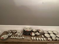 Full overview of the dish set including plates, bowls, and spoons arranged on a wooden table.