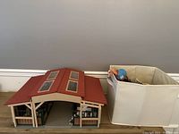 Overall view of the Schleich barn with red roof and bin of animals beside it