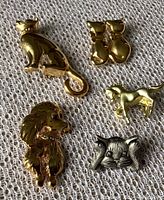 Front view of five animal brooches showing three cats, one dog, and one horse on fabric background.