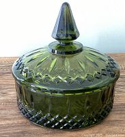 Side view of vintage avocado green cut glass lidded candy dish showing detailed cut glass design and pointed finial lid.