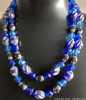 Photo showing layered double and triple strand beaded necklaces with cobalt blue, black, and silver-tone patterned beads