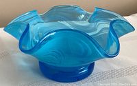 Side view of the blue ruffled edge glass bowl showing swirl patterns and curved rim shape