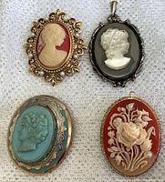 Top view of four cameo pieces laid out on cloth surface showing carved faces and floral motif