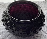 Side view of the oval-shaped amethyst hobnail glass bowl showing the raised dotted hobnail pattern on the exterior and the depth of the bowl.