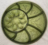 Top-down photo of avocado green Indiana Glass divided platter with deviled egg section and five additional compartments.