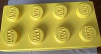 Close-up of yellow Lego container lid with Lego logos on the studs
