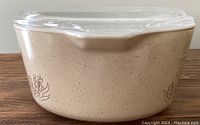 Side view of beige speckled Pyrex casserole dish with mushroom and grass pattern on side