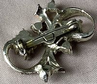 Back view of a gold-tone floral rhinestone brooch showing the standard pin clasp attachment.