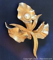 Front view of the gold toned orchid flower brooch with pearl at the center, showing detailed petals and leaves.