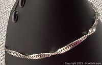 Silver twisted chain anklet displayed on black stand, showing the full length and twisted design.