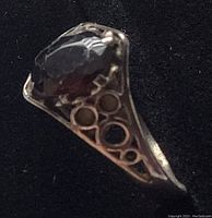 Side view of silver ring showing black faceted stone and intricate cutout pattern on band.
