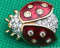Close-up photo of front of Swarovski ladybug brooch showing red enamel wings accented with clear crystals
