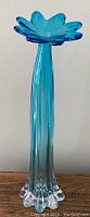 Front view of tall blue vase with flower-shaped top and clear base