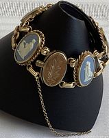 Front view of vintage Wedgwood blue jasperware bracelet with five panels showing classical white relief figures and detailed gold-tone clasp with safety chain.